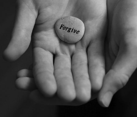 Hands holding stone that says "forgive"