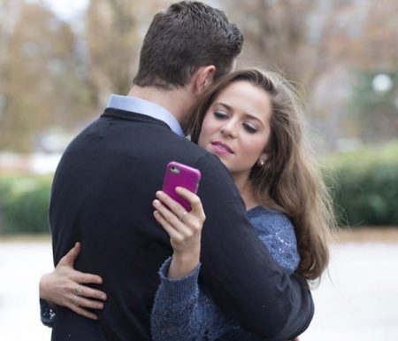 Women playing on her phone while hugging her husband
