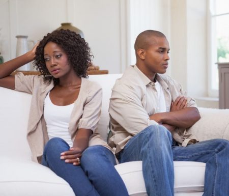 Couple on couch looking upset with one another