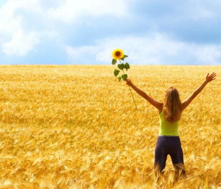 Lady in the middle of a field standing with arms wide open