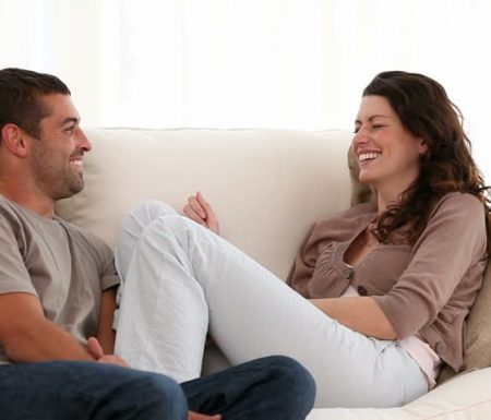 Couple relaxed on couch talking to one another