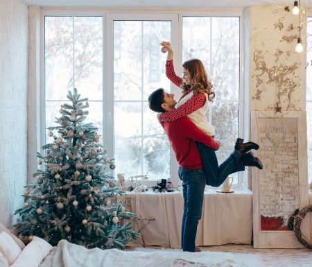 Husband picking up wife next to a Christmas tree