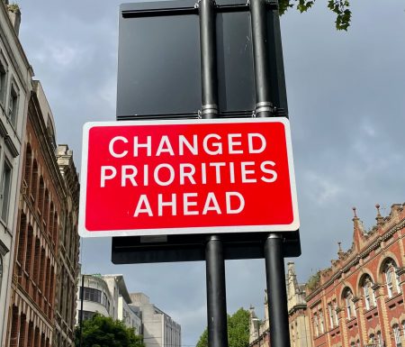 Sign that says "changed priorities ahead"