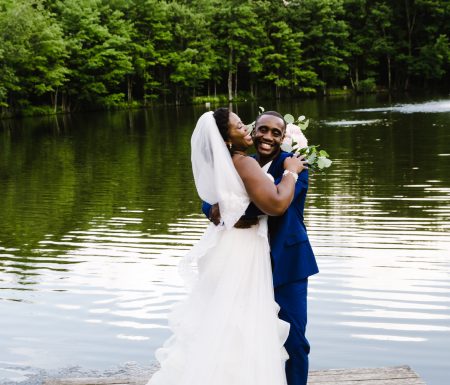 black couple posing next to a lake on their wedding day
