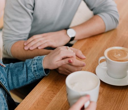 Couple holding hands drinking coffee