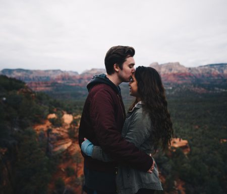 Man kissing women on forehead overlooking mountains and trees