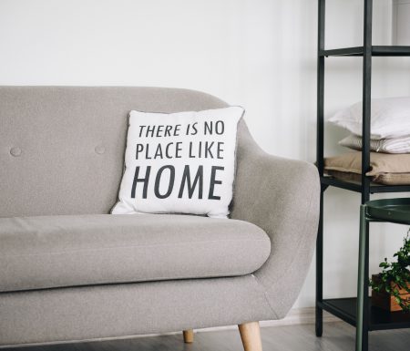 Couch with a pillow that says "There is no place like Home"