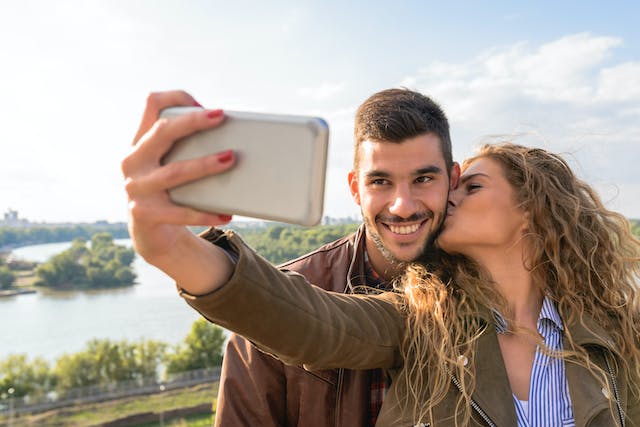 Couple taking a selfie with the women kissing the man on the cheek